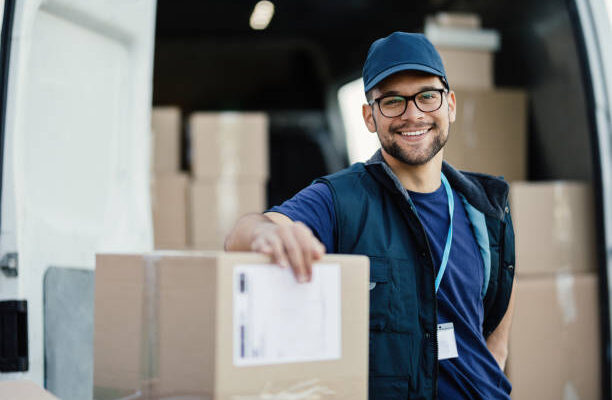 istockphoto-1186576767-612x612 Portrait of happy worker unloading boxes from a delivery van and looking at camera.
